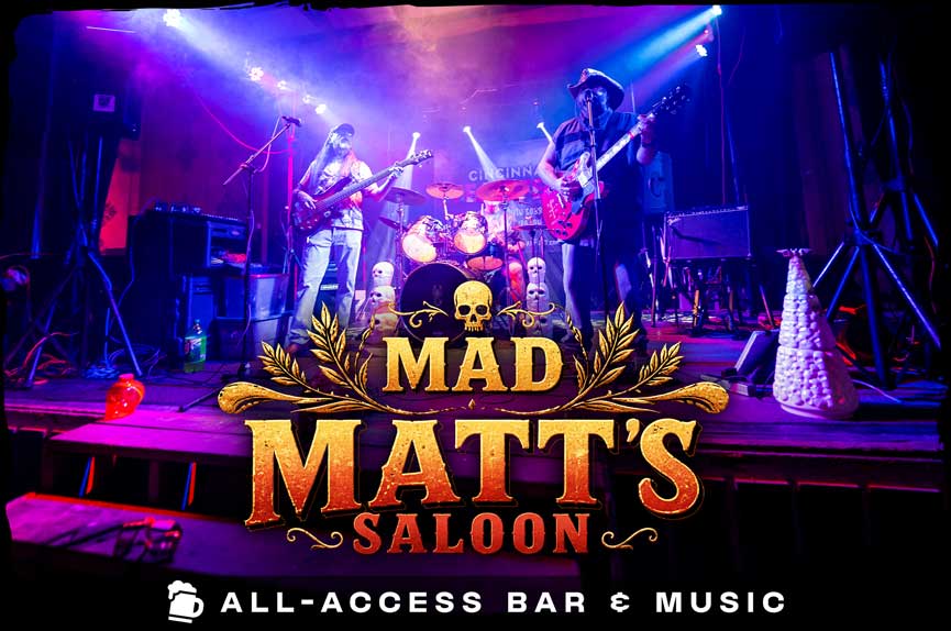 A live rock band performs on a stage bathed in vibrant blue and purple concert lighting, with decorative skulls lining the front edge. The text reads "Mad Matt's Saloon. All-Access Bar & Music."